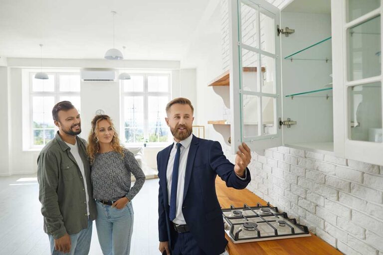 Homeowners reviewing sale documents at a kitchen table beside a tidy, prepared living room.